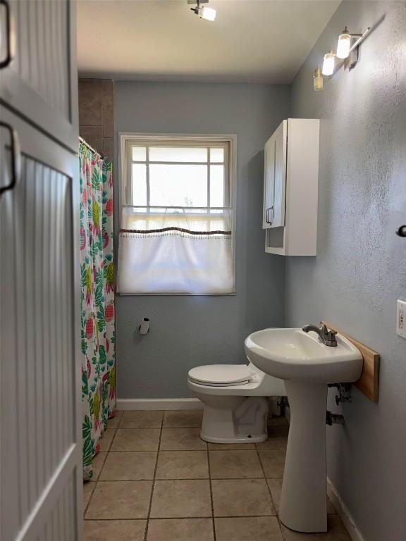 full bath featuring toilet, a shower with curtain, tile patterned flooring, and baseboards
