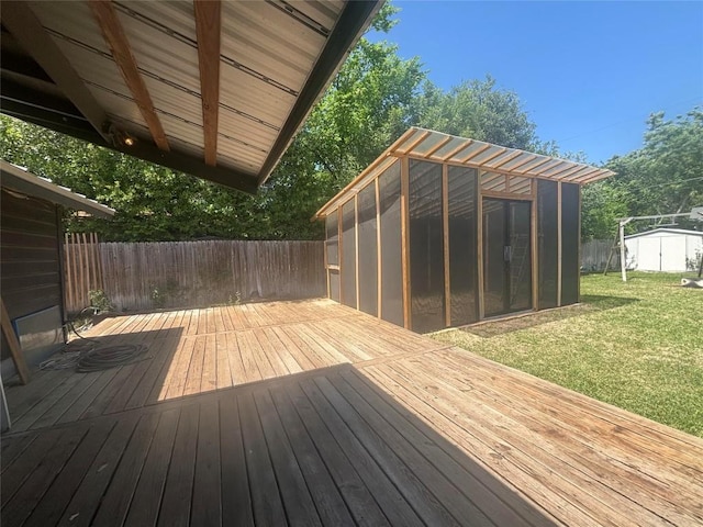 deck with a lawn, fence, an outdoor structure, and a sunroom
