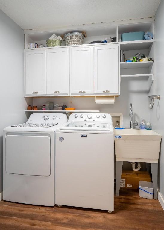 laundry area with wood finished floors, washer and clothes dryer, and cabinet space