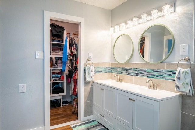 bathroom with double vanity, a sink, wood finished floors, and a spacious closet