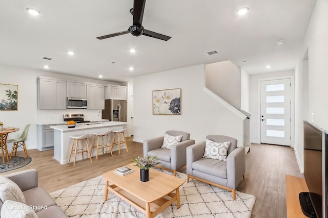 living room featuring visible vents, light wood-type flooring, a ceiling fan, and recessed lighting