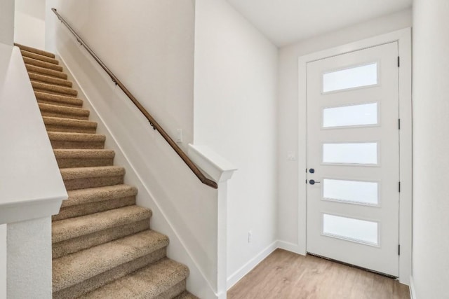 entryway with baseboards, stairway, and light wood-type flooring
