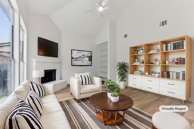 13113 Bennington Ln, Austin, TX 78753 - living area with light wood-style flooring, ceiling fan, a brick fireplace, and high vaulted ceiling