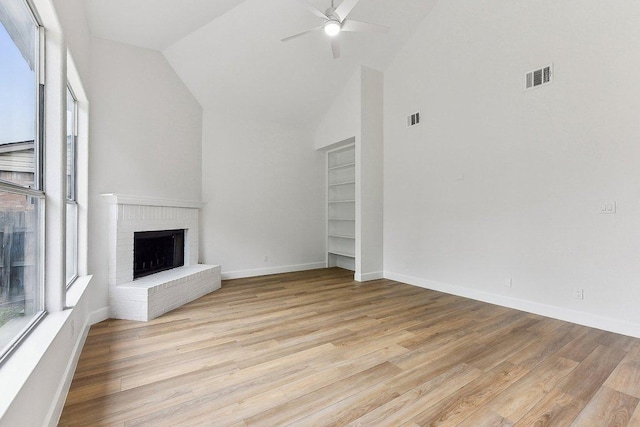 unfurnished living room featuring a brick fireplace, light wood finished floors, a ceiling fan, and visible vents
