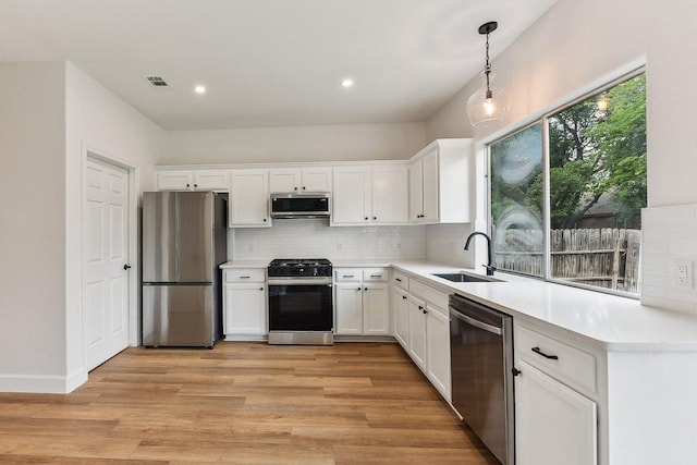 kitchen with white cabinetry, visible vents, stainless steel appliances, and a sink