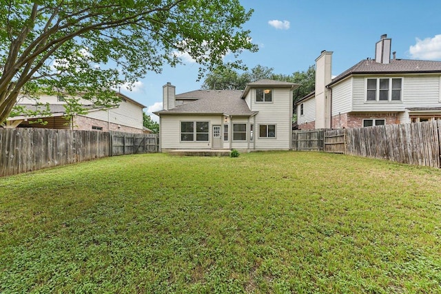 rear view of property with a lawn and a fenced backyard