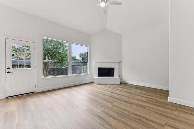 unfurnished living room featuring ceiling fan, baseboards, vaulted ceiling, a brick fireplace, and wood finished floors