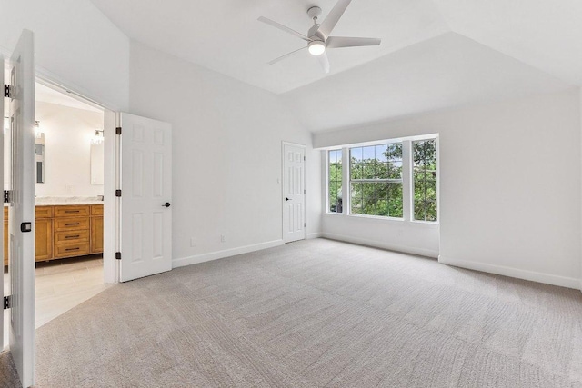 unfurnished bedroom with baseboards, light carpet, ensuite bath, and vaulted ceiling