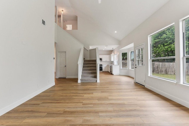 unfurnished living room featuring stairs, visible vents, light wood-style floors, and plenty of natural light