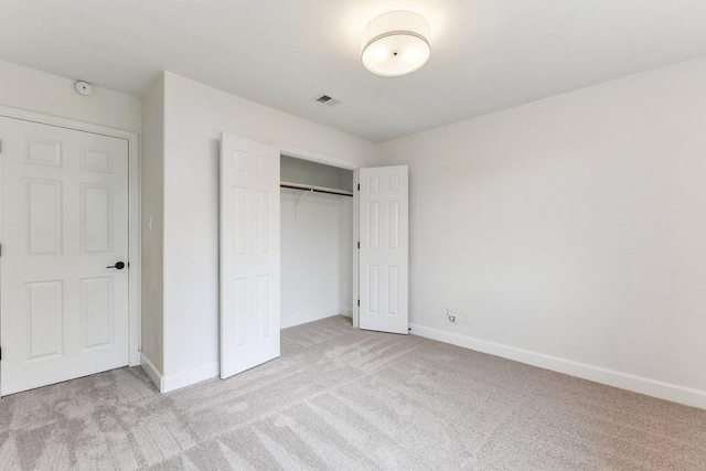 unfurnished bedroom with baseboards, visible vents, light carpet, and a closet