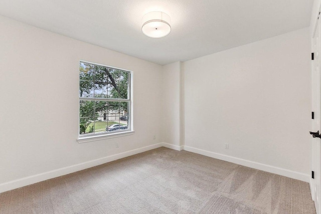 carpeted empty room featuring baseboards