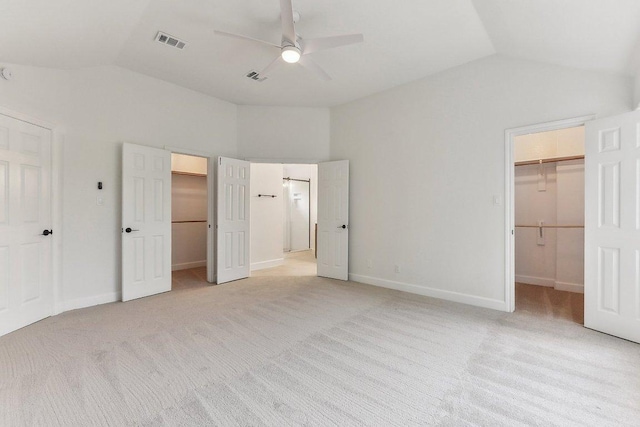 unfurnished bedroom featuring visible vents, a spacious closet, a closet, and lofted ceiling
