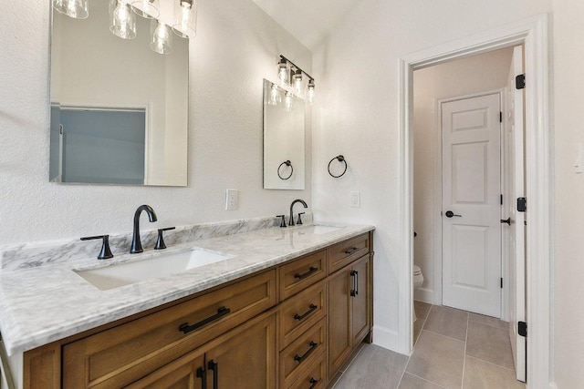 bathroom featuring toilet, double vanity, a sink, and tile patterned flooring