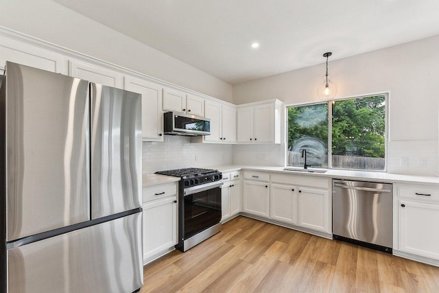 kitchen with appliances with stainless steel finishes, light countertops, white cabinets, and a sink