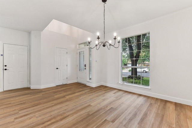 unfurnished dining area with ornamental molding, baseboards, a chandelier, and light wood-type flooring