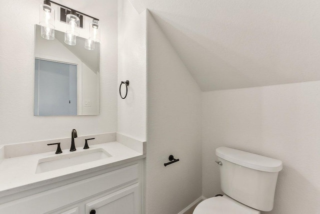bathroom with lofted ceiling, vanity, and toilet