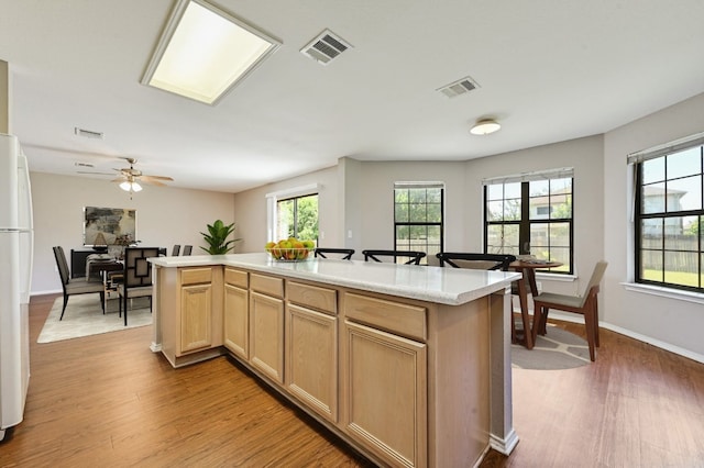 kitchen with visible vents, wood finished floors, light countertops, and freestanding refrigerator