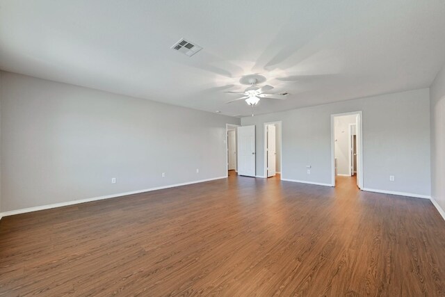 empty room featuring baseboards, visible vents, ceiling fan, and dark wood-style floors