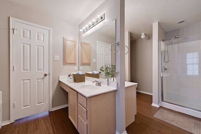 bathroom featuring walk in shower, vanity, and wood finished floors