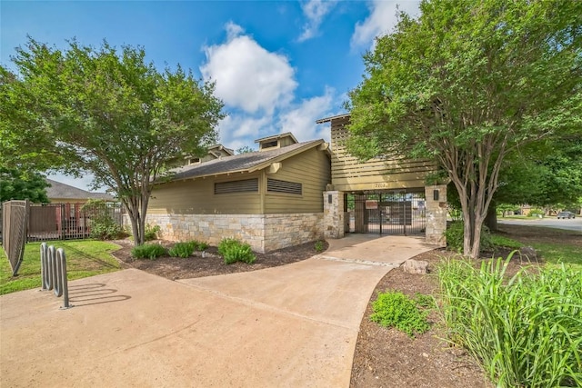 exterior space with fence, stone siding, and a gate