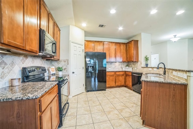 kitchen featuring a sink, visible vents, black appliances, a peninsula, and brown cabinetry