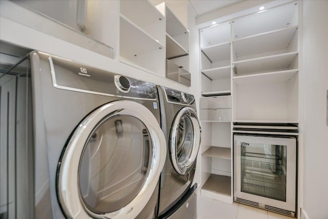 laundry area featuring beverage cooler, washing machine and clothes dryer, laundry area, and light tile patterned floors