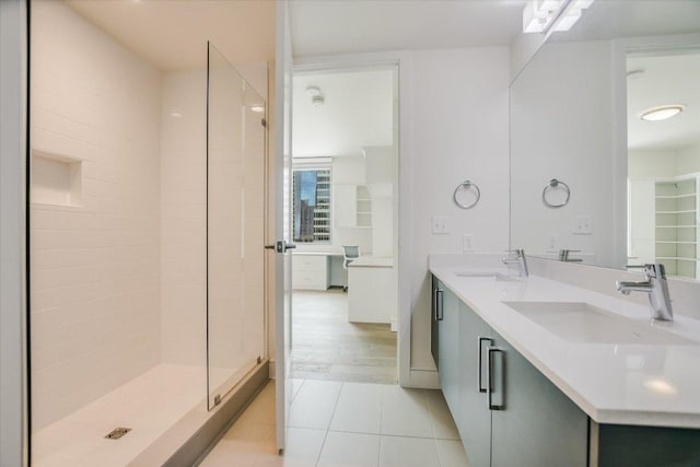 full bath featuring tile patterned floors, a shower stall, double vanity, and a sink