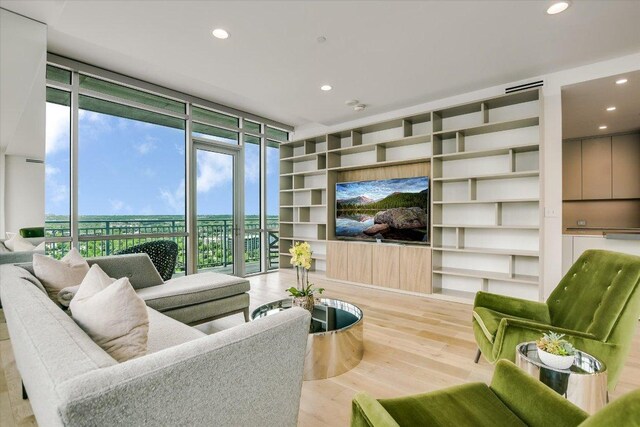 living room featuring recessed lighting, built in features, expansive windows, and wood finished floors