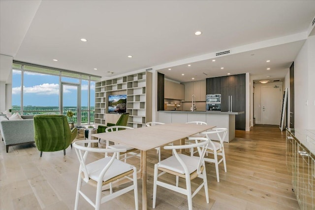 dining room featuring recessed lighting, light wood finished floors, visible vents, and floor to ceiling windows
