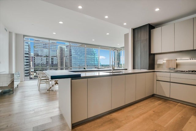 kitchen with gas cooktop, a peninsula, plenty of natural light, and light wood-style flooring