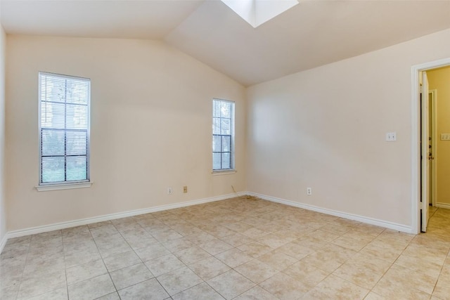 empty room with lofted ceiling with skylight, light tile patterned flooring, and baseboards