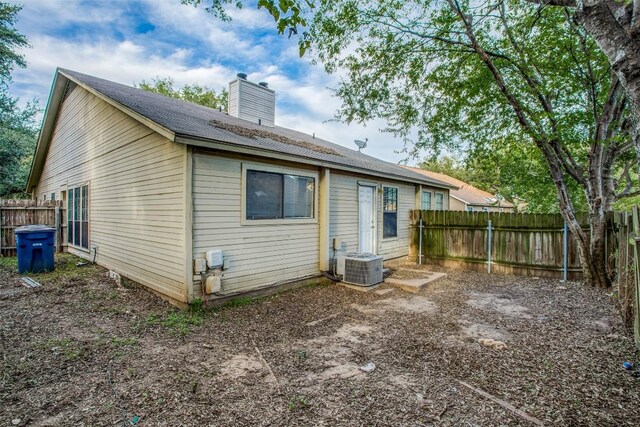 back of house with a chimney, fence, and central AC