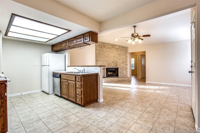 kitchen with a brick fireplace, dishwasher, a sink, and light tile patterned flooring