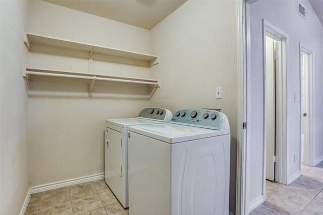 washroom with washing machine and dryer, light tile patterned flooring, laundry area, visible vents, and baseboards