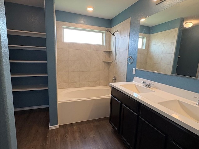 full bathroom with wood finished floors, shower / bathing tub combination, double vanity, and a sink