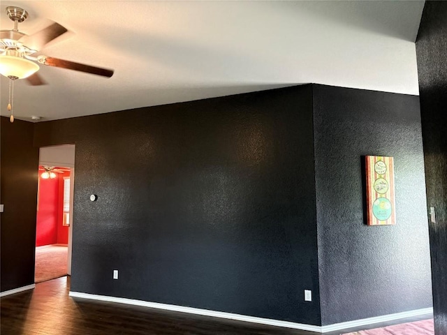 unfurnished room featuring wood finished floors, a ceiling fan, a textured wall, and baseboards