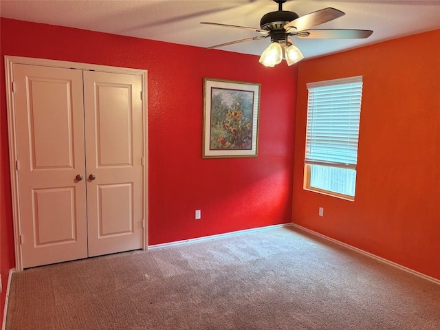 unfurnished bedroom with baseboards, ceiling fan, a closet, and carpet flooring