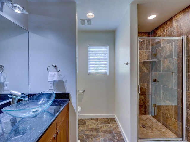 bathroom with visible vents, a stall shower, baseboards, toilet, and vanity
