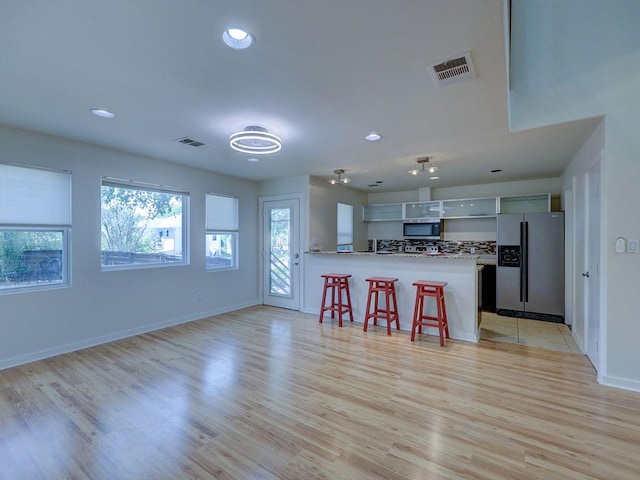 kitchen featuring recessed lighting, a kitchen bar, visible vents, and appliances with stainless steel finishes