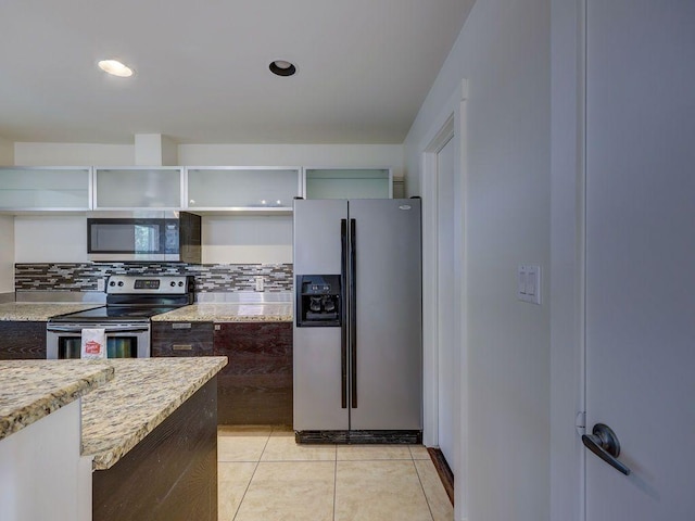 kitchen featuring stainless steel appliances, open shelves, light stone counters, and decorative backsplash