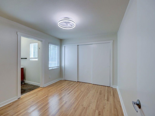 unfurnished bedroom featuring baseboards, a closet, and light wood finished floors