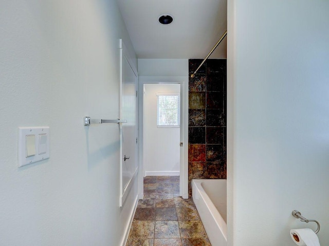 full bath with shower / washtub combination, stone tile floors, and baseboards