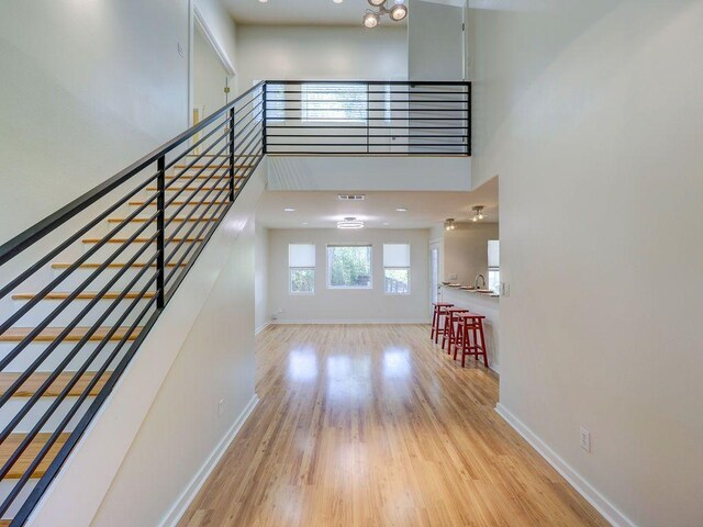 foyer entrance featuring baseboards, wood finished floors, and a high ceiling