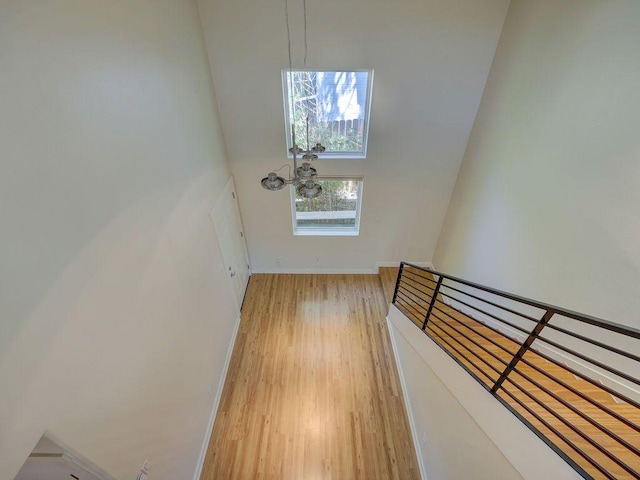 doorway featuring baseboards, light wood finished floors, and a towering ceiling