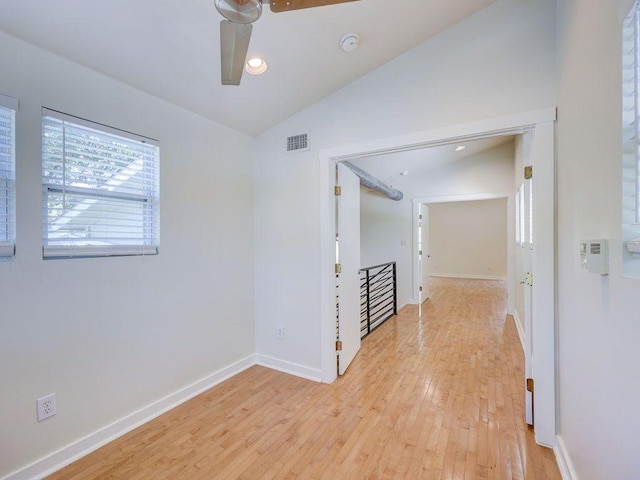 empty room with light wood finished floors, baseboards, visible vents, a ceiling fan, and lofted ceiling