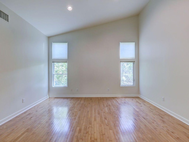 empty room featuring recessed lighting, light wood-style floors, baseboards, visible vents, and lofted ceiling