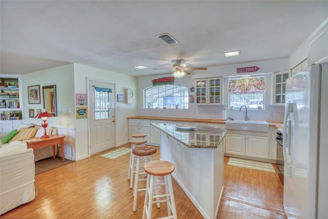 1833 Highland Dr, Marble Falls, TX 78654 - kitchen with a sink, a kitchen breakfast bar, visible vents, a kitchen island, and freestanding refrigerator