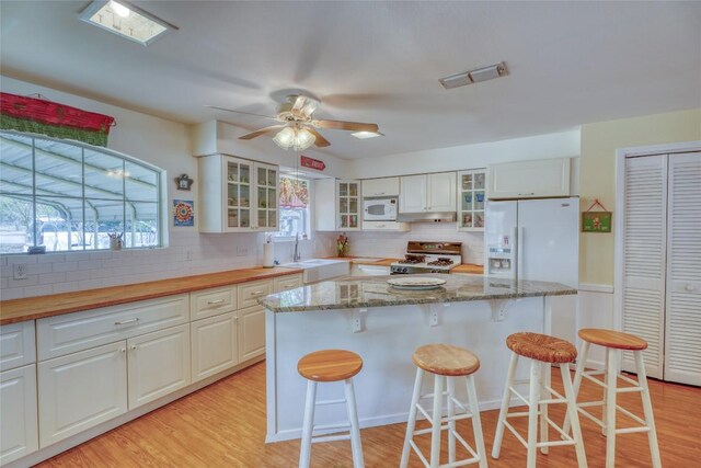 1833 Highland Dr, Marble Falls, TX 78654 - kitchen with decorative backsplash, light wood-style flooring, a sink, visible vents, and white appliances