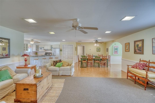 1833 Highland Dr, Marble Falls, TX 78654 - living room with arched walkways, a ceiling fan, wainscoting, and light colored carpet