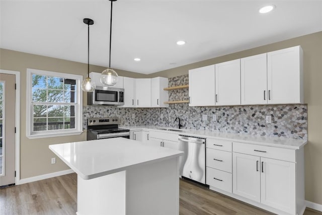 kitchen featuring a sink, open shelves, stainless steel appliances, and light countertops